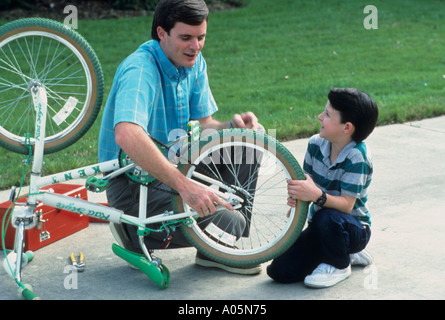 Père et fils à l'extérieur de la chaîne de réglage sur la roue arrière d'un vélo Banque D'Images