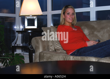 20 yr old woman relaxing at home sur le canapé en regardant la télé Banque D'Images