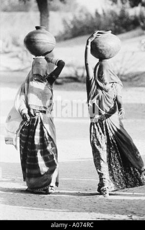 Deux dames visages couverts au puits pour chercher de l'eau le Rajasthan en Inde Banque D'Images