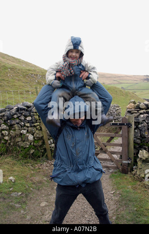 Enfant grimper sur les épaules du père au cours d'une balade en campagne, UK Banque D'Images