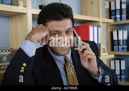 Le PDG parle de mobile debout dans sa cabine de bureau en costume d'affaires - MR# Banque D'Images