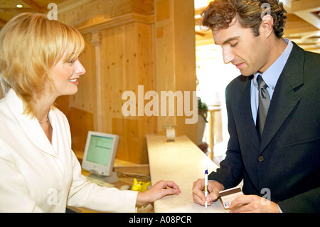 Beim Mann Hotelrezeption Einchecken Bezahlen an der, l'homme de payer à la réception Banque D'Images
