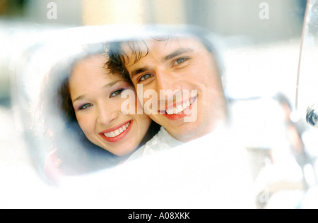 Réflexion d'un couple smiling dans un rétroviseur Banque D'Images