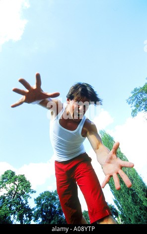 Low angle view of a young man se pencher avec ses bras reaching out Banque D'Images