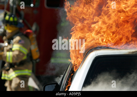 Feu de voiture avec les pompiers sur les lieux s'apprête à éteindre l'incendie Banque D'Images