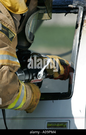 Fire fighter avec un tuyau pour éteindre le feu dans une voiture Banque D'Images