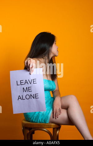 Young Asian woman holding a sign reading, 'laisse-moi tranquille". Banque D'Images