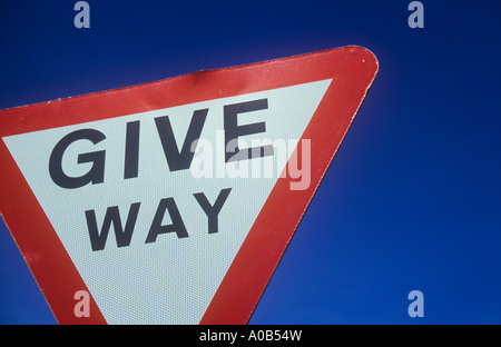 Close up de la partie de rouge et blanc à l'envers façon triangulaire roadsign affirmant donner avec ciel bleu profond Banque D'Images