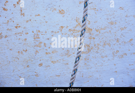 Close up of blanc jaune et bleu de la corde de nylon strand pendants devant un arrière-plan tacheté blanc et ocre Banque D'Images