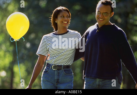 African American couple walking arm in arm et tenant un ballon jaune Banque D'Images