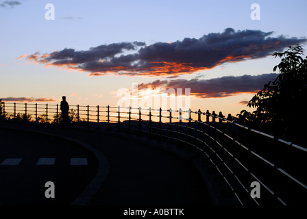 Une seule personne se tenant près d'une barrière de rail en regardant le coucher du soleil sur Oslo depuis un point de vue à Ekeberg appelé utsikten. Banque D'Images