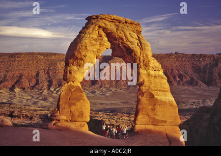 Groupe de randonneurs ajoute à grande échelle Delicate Arch au coucher du soleil, des Arches nat Park, Utah, USA Banque D'Images