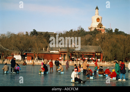 Chine Pékin patineurs sur un lac gelé dans le Parc Beihai et l'île de jade Le Dagoba blanc Banque D'Images