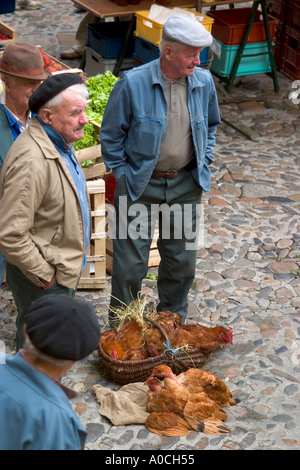 De vieux hommes vendre les poulets à un marché de village Banque D'Images