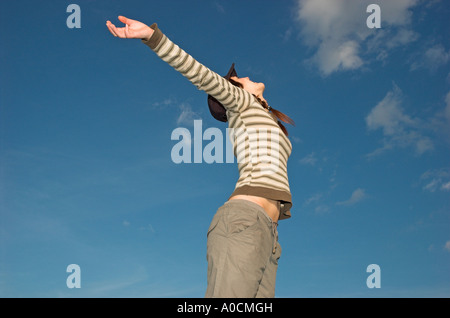 Jeune femme aux tresses wearing cap standing outdoors bras tendus Banque D'Images