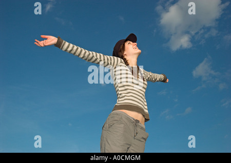 Jeune femme aux tresses wearing cap standing outdoors bras tendus Banque D'Images