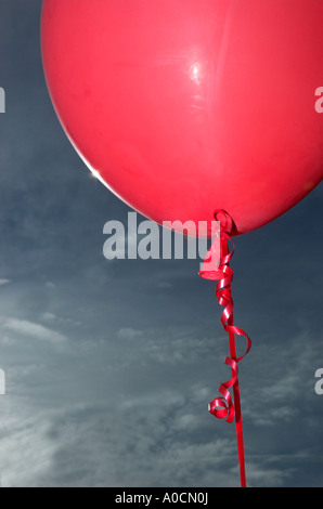 Fermer la vue d'un ballon rouge attaché avec un ruban frisé contre le ciel bleu Banque D'Images