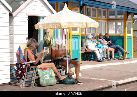 Un couple de retraités en dehors de leurs cabanes de plage SUR LA PROMENADE ET MARINE PARADE À PAIGNTON DEVON UK Banque D'Images