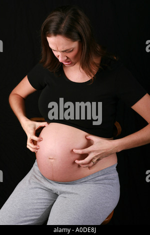 Beaucoup attendent femme enceinte maman soit dans le troisième trimestre les rayures démange sa bosse apparente de la peau de l'estomac symptômes de grossesse Banque D'Images