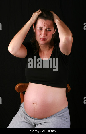 Jeune femme enceinte à 34 semaines au troisième trimestre avec triste émotions concernés inquiète l'expression du visage exposé bump Banque D'Images