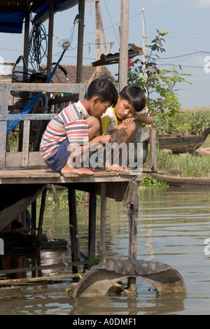 Delta du Mékong Vietnam Chau Doc village flottant deux garçons jouant sur une véranda de ferme du poisson Banque D'Images