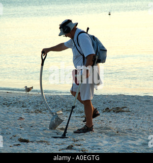 Bonita Springs beach Floride USA Beachcomber en utilisant un détecteur de métal sur la côte du golfe au coucher du soleil Banque D'Images