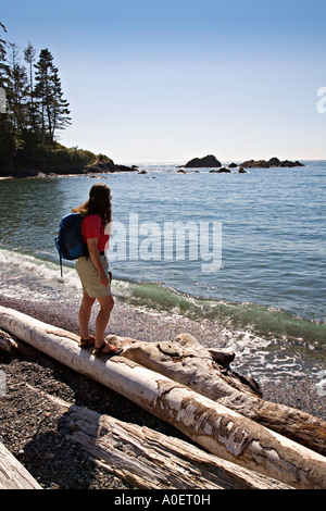 Female hiker debout sur les journaux de bois flotté sur la plage col Deception state park l'état de Washington, USA Banque D'Images