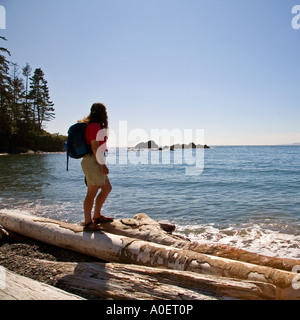 Female hiker debout sur les journaux de bois flotté sur la plage col Deception state park l'état de Washington, USA Banque D'Images