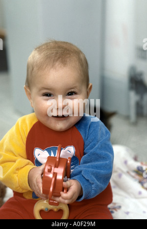 Baby sitting sur le sol en jouant avec des jouets Banque D'Images