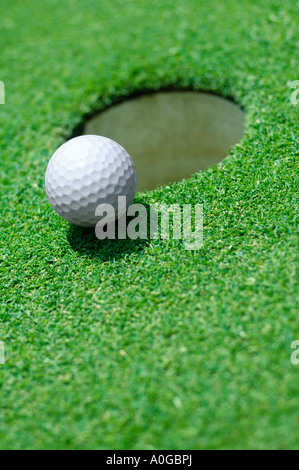 Balle de golf au bord du trou sur le green de golf Banque D'Images