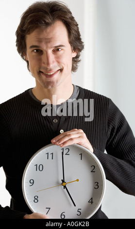 Smiling man holding réveil Banque D'Images