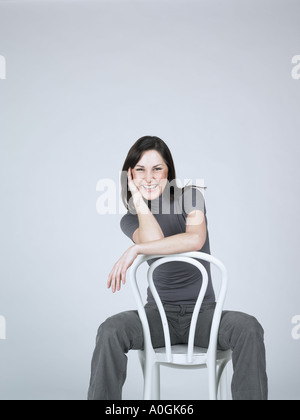 Smiling woman sitting on a chair Banque D'Images