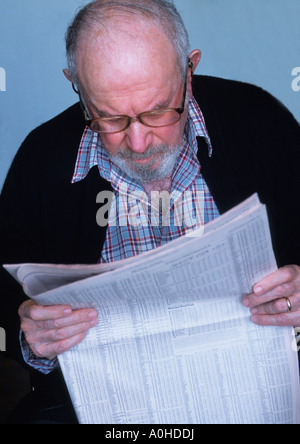 homme âgé lisant la page financière du journal vérifiant le bourse et ses investissements Banque D'Images