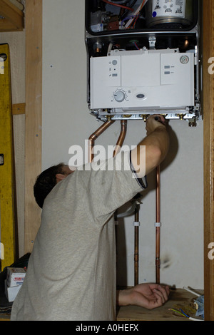 L'installation de nouveaux travailleurs mâles adultes à l'aide d'une tuyauterie de gaz à souder les joints sur une nouvelle chaudière pour le chauffage central Banque D'Images