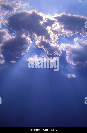 Poutres de soleil, nuages sombres et ciel bleu. Soleil brillant derrière le nuage de cumulus. Banque D'Images