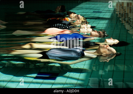 Les jeunes femmes enceintes flotter sereinement dans une piscine lors d'une classe d'exercice pré Banque D'Images
