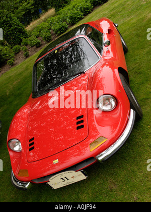 Classic rouge lumineux Ferrari Dino 246 GT garée sur une pelouse avec bouclier rallye attaché Banque D'Images