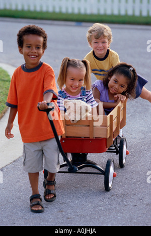 Portrait de deux garçons et deux filles jouant avec un push cart Banque D'Images