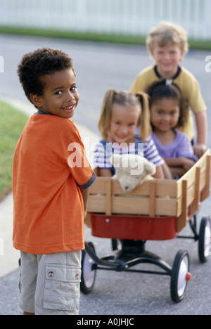 Portrait de deux garçons et deux filles jouant avec un push cart Banque D'Images