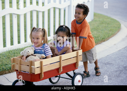 Garçon et deux filles jouant avec un push cart Banque D'Images