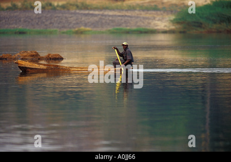 La pagaie de pirogue pêcheur autochtone dans la lumière du soir sur le Zambezii River, Afrique Banque D'Images