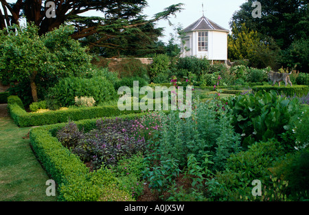 Bordure de buis taillés, de parterres carrés summerhouse blanc en arrière-plan Banque D'Images