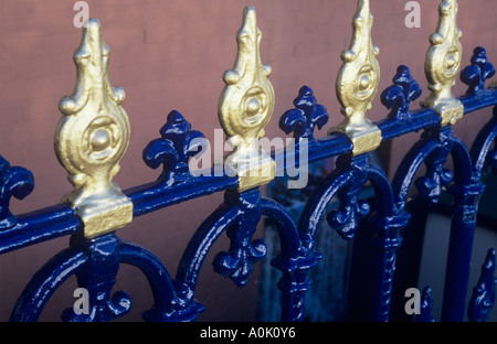 Close up of ornate balustrade en métal peinte en bleu et l'or en face de mur peint en rose saumon indirecte du soleil chaud Banque D'Images