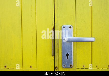 Close up detail de porte en bois teinté jaune vif sur une cabane ou un local ou de kiosque ou de la cabine avec la poignée de porte en aluminium Banque D'Images