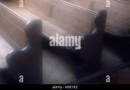 Des bancs d'église en bois simple avec un rouge et d'un livre bleu allongé sur un siège et avec du parquet conseil Banque D'Images