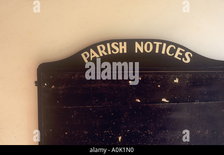 Détail d'un parquet en bois noir d'affichage des avis déposés sur le mur pâle dans la lumière chaude et dirigé Paroisse Avis importants Banque D'Images