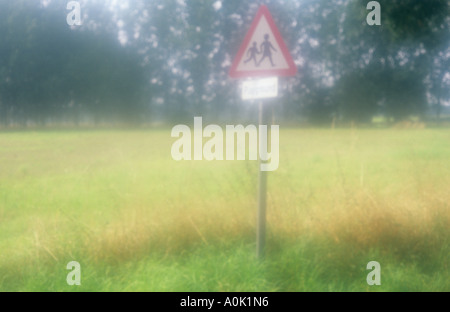 Roadsign impressionniste sur bord champ avec de longues herbes et arbres lointain avertissement que les enfants peuvent être autour de jeux pour enfants Banque D'Images