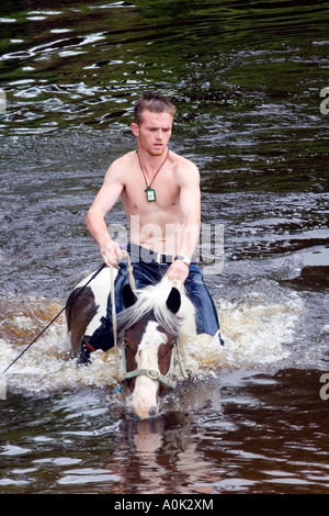 Un homme monte un cheval dans une rivière Banque D'Images