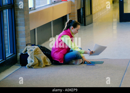 High school girl student est assis sur le sol dans un couloir Banque D'Images