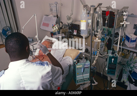 Une infirmière du personnel masculin de l'oxygène à un patient donné dans l'unité de soins intensifs d'un hôpital de Londres, UK Banque D'Images